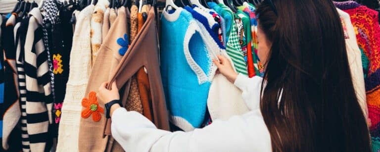 Person schaut sich Second Hand Oberteile an